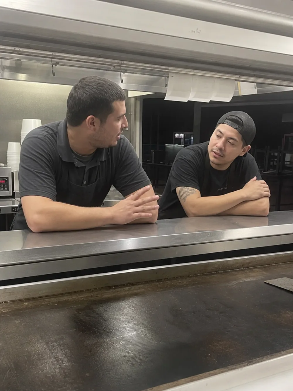Two cooks talking across the pass after the last ticket of the night