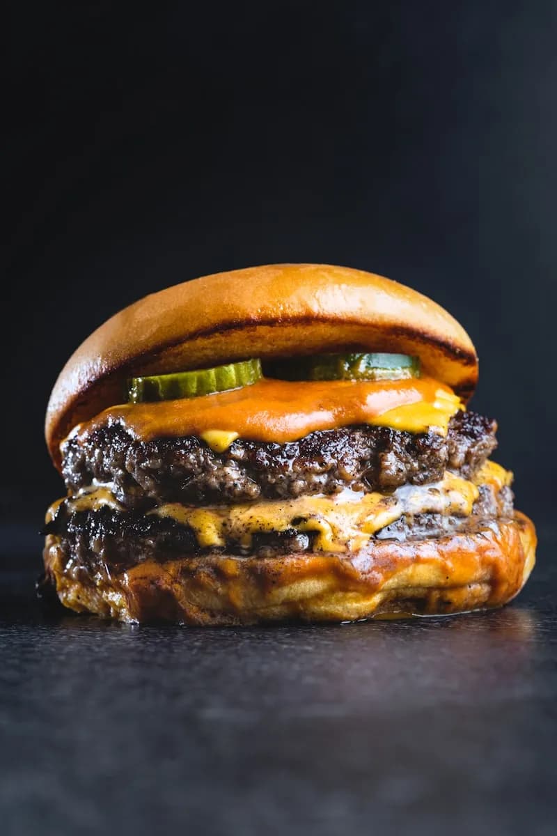 Double cheeseburger with pickles and sauce on a glossy bun