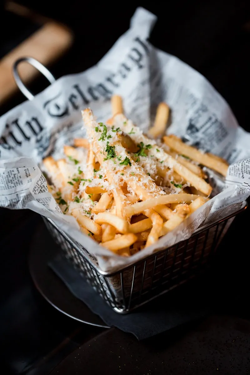 Fries in a wire basket dusted with parmesan and parsley